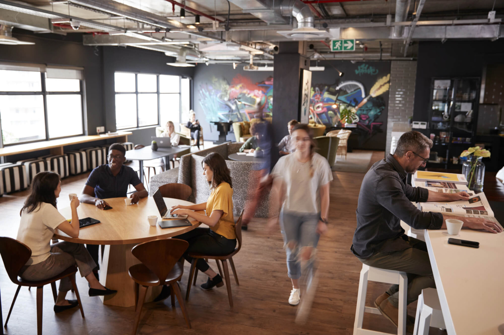 Dynamic coworking space with a mix of collaborative zones, casual seating areas, and creative murals, designed for networking and focused work.