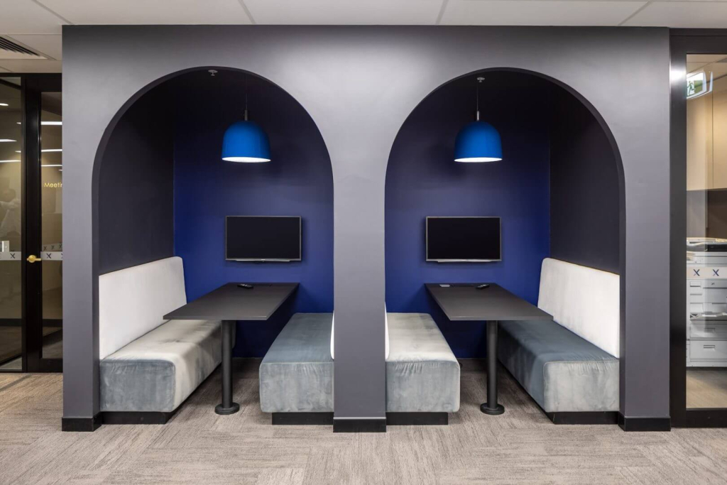 Modern office design with enclosed meeting booths, featuring comfortable seating, vibrant colours, and technology for private discussions.