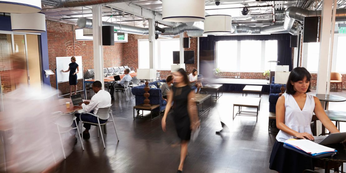 Industrial-style coworking space featuring an open layout with flexible event space, meeting areas, and ample natural light to encourage collaboration.